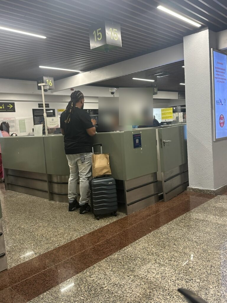 SDQ immigration hall, numbered passport control stations, faces blurred for privacy