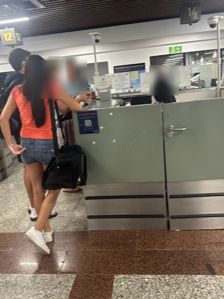 SDQ immigration hall, numbered passport control stations, faces blurred for privacy